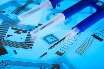 RFID implantation syringes and chips on RFID tags (Radio Frequency Identification tags), blue background