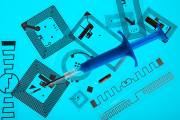 RFID implantation syringe and chips on RFID tags (Radio Frequency Identification tags), blue background