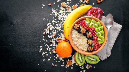 Obraz na płótnie Canvas Healthy food: porridge with fruit kiwi, banana and nuts. On Wooden background. Top view.