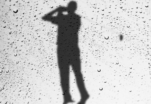 glass window wih raindrops as it looks a golfer