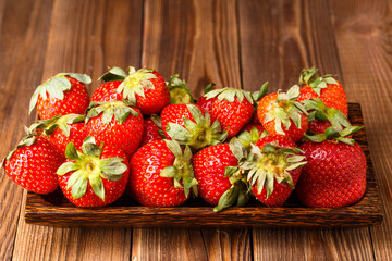 Ripe strawberry on wooden plate