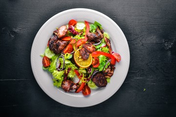 Salad with fresh cucumbers, tomatoes and greens with grilled meat on a plate Wooden board. Top view. Free space.