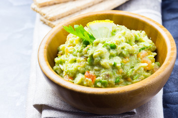 Homemade guacamole and crisps on dark background.