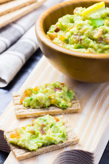 Delicious guacamole in wooden bowl on wooden board.