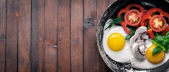 Fried egg with herbs and vegetables in a frying pan. Top view. Free space.