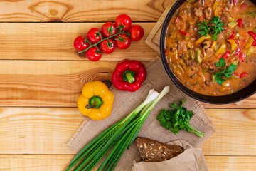 Stew with meat and vegetables in tomato sauce on wooden background. Top view