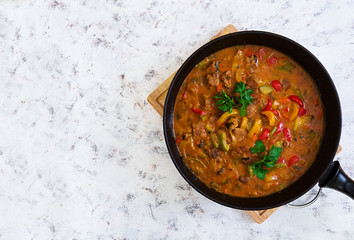Stew with meat and vegetables in tomato sauce on white background. Top view