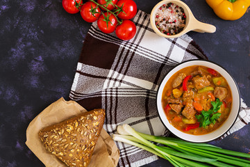 Stew with meat and vegetables in tomato sauce on dark background