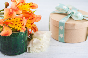 Arrangement of orange lily flowers in green pot, gift box