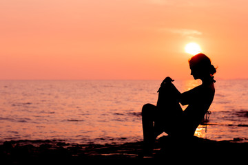 Fototapeta na wymiar Woman silhouette sitting on sunset sea background, side view, back lit