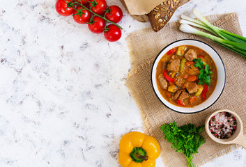 Stew with meat and vegetables in tomato sauce on white background. Top view