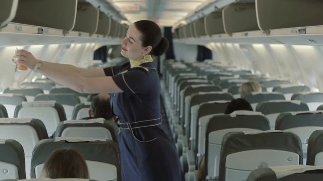 Young stewardess gives the instructions about oxygen masks