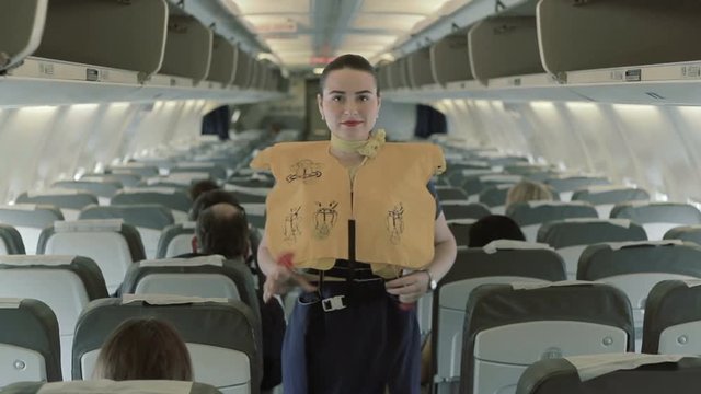 Young stewardess shows the manipulations with the life vest