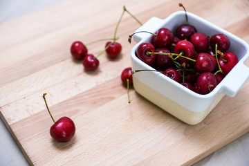 Naklejka na ściany i meble Cherries in the ceramic bowl on the wooden board