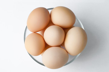 Brown Hen eggs in glass bowl on white table. Fresh farmer's egg. Top view