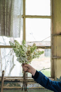 Arm holding bouquet of flowers against window