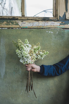 Junge h&auml;lt selbst gepfl&uuml;ckte Blumen in der Hand vor der Wand eines sehr alten Geb&auml;udes