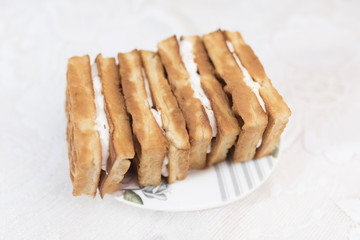 Viennese waffles with cream filling are on a white saucer with a floral pattern on a white lace background