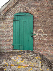 Old green wooden door on a brick barn