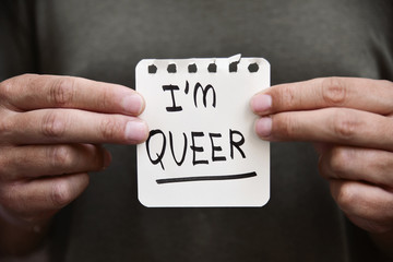 young man with a note with the text I am queer - obrazy, fototapety, plakaty