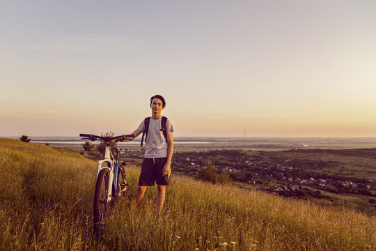 Young boy with a bicycle on a hill