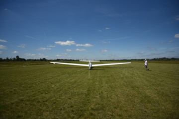 Sailplane landing on a grass, sunny day in Szczecin.