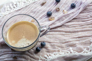 One cup of espresso on the pink tissue with several blueberries and sugar