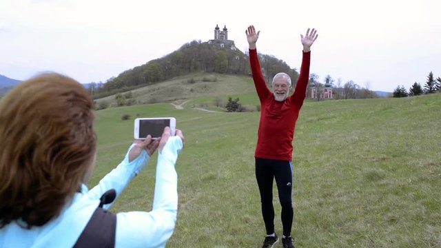 Active senior runners in nature taking photo with smart phone.
