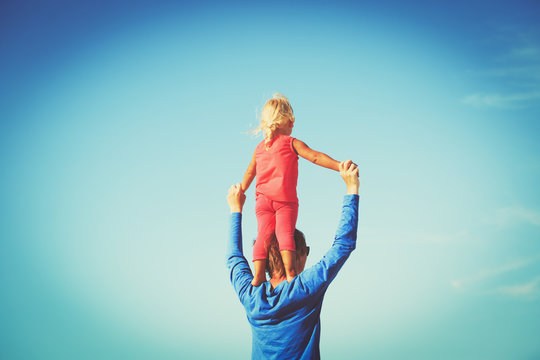 father and daughter on shoulders play at sky