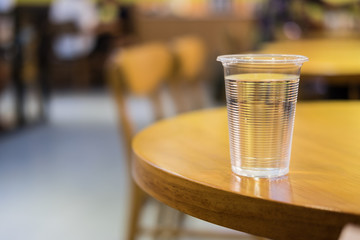 Plastic cup of water on round wooden table