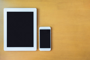 Top view of smart phone and tablet on wood table