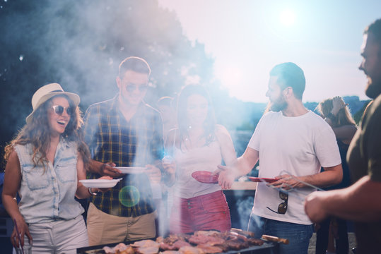 Group of friends eating, drinking, dancing and having a good time at outdoor party