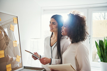 Two pretty cheerful multiracial designers with tablet
