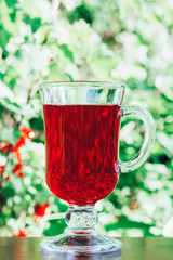 glass with red fruit berry drink natural green background closeup