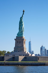 Fototapeta premium Statue of Liberty island and New York city skyline in a sunny day, blue sky