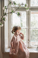 Kleines Mädchen in Kleid guckt aus dem Fenster