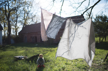 Kleines Kind schaut zu, wie die Wäsche auf der Leine im Wind flattert