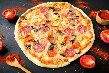 Italian pizza with tomato and spices on dark background. Top view.