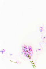 Bouquet of pink flowers and purple shabby tapes on white background. Flat lay, top view. Beauty background