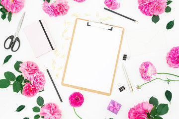 Styled wedding workspace with clipboard, notebook, pink roses, ranunculus and accessories on white background. Flat lay, top view.
