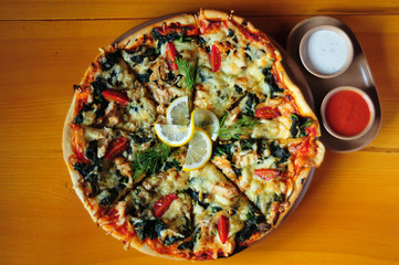 Pizza with trout, tomato, spinach and cheese with garlic and tomato sauce.