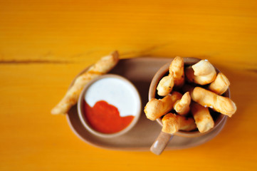 Bread sticks in cup with garlic and tomato sauce