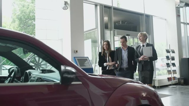 The manager talks about the car to young couple in car dealership