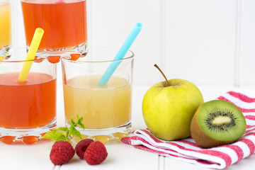 Collage of glasses with fresh delicious smoothie juice and straw on board background colourful for kids party