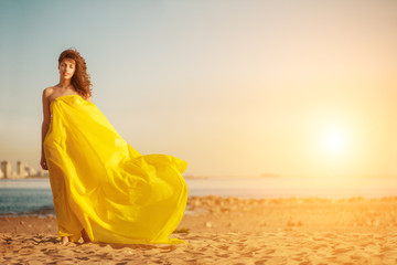Fashion girl in a long dress against a summer sunset background. A beautiful model on the beach...
