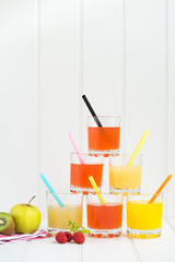Collage of glasses with fresh delicious smoothie juice and straw on board background colourful for kids party