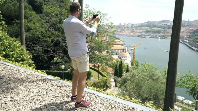 Young man taking photo with view of Porto standing in garden
