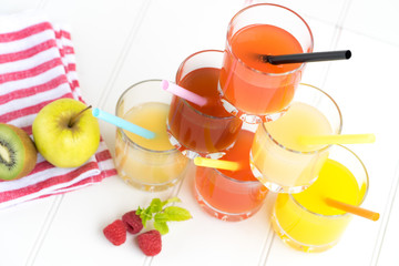 Collage of glasses with fresh delicious smoothie juice and straw on board background colourful for kids party