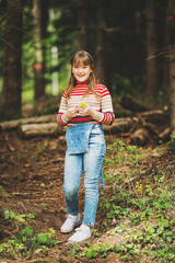 Cute little girl enjoying fresh spring forest, wearing denim overalls and warm pullover