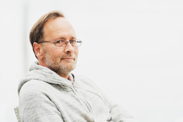 Outdoor portrait of 50 year old man wearing grey hoody and eyeglasses